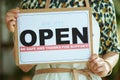 Modern business owner woman in apron showing open sign