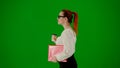 Portrait of attractive office girl on chroma key green screen. Woman in skirt and glasses walking holding red folder and Royalty Free Stock Photo