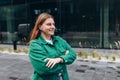 Modern business woman standing near Office Building. Crossed arms. Huge blurred office windows on the background. High Royalty Free Stock Photo