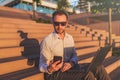 Modern businessman holding mobile phone and laptop while sitting on outdoor steps Royalty Free Stock Photo