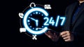 Modern Businessman Holding Tablet with Neon 24 hour Support Icon Representing Around the Clock Customer Service and Royalty Free Stock Photo
