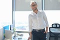 Modern businessman looking at camera and smiling while standing in the office