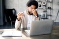 A modern businessman rubs his eyes in fatigue or exasperation while working on his laptop Royalty Free Stock Photo