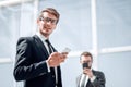 Modern businessman with a smartphone on background office