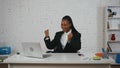 Modern businesswoman creative concept. Woman sitting at the desk smiling happily throwing hands up in the air, pumping
