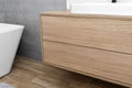 A modern cabinet hanging on the washbasin in the bathroom with a matte black faucet, the floor is covered with ceramic tiles imita