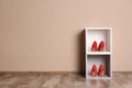 Modern cabinets with high heeled shoes near color wall