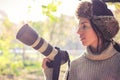 Modern camera with a large lens in hand of young photographer girl and ready to take photo. Royalty Free Stock Photo