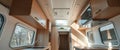 Modern camper van interior with sunlight streaming through windows. Light wood cabinets and appliances create a bright, airy space Royalty Free Stock Photo