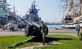 Modern cannon on the navy pier of Russian Pacific Fleet. Moored sailing ship `Pallada` and modern battleship are on background. Royalty Free Stock Photo