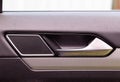 Modern car door trim with tweeter and door handle with metal insert, close-up