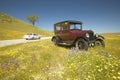 A modern car driving by a maroon Model T parked alongside a scenic road surrounded by spring flowers, Route 58, Shell Road, CA