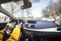 Modern car interior with driver female hands on steering wheel, winter snowy landscape outside. Safe driving concept Royalty Free Stock Photo