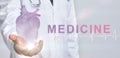 Modern cardiology. Woman doctor in white coat holds glowing heart hologram in hand