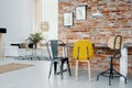 Modern chairs at dining table against red brick wall with posters in bright apartment interior. Real photo Royalty Free Stock Photo