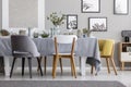 Modern chairs at table with tableware in grey dining room. Real photo