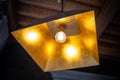 Modern chandelier hanging from the ceiling with gold leaf and a simple shape and a single lamp shines with warm light Royalty Free Stock Photo