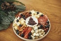 Modern cheese platter with different cheeses, salami and prosciutto, nuts and cranberry sauce as christmas tree on festive table.