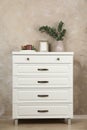 Modern chest of drawers with decor near beige wall