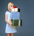 Modern child on grey holding pile of christmas present boxes Royalty Free Stock Photo