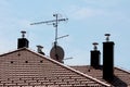 Modern chimneys with new shiny metal pipes on top surrounding tall metal pole with multiple TV antennas on top of family house Royalty Free Stock Photo