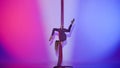 Portrait of female acrobat isolated on pink purple neon background. Girl aerial dancer performing balancing element on