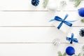 Modern Christmas flatlay composition. Gift box with blue ribbon bow, decorations, fir tree branch on white wooden background. lat Royalty Free Stock Photo