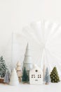 Modern christmas scene, miniature snowy village on white table. Merry Christmas! Stylish little Christmas trees and house