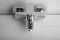 A modern chrome faucet is shown installed against a white bathroom wall. Royalty Free Stock Photo