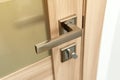 Modern chrome metal door handle on wooden door. Royalty Free Stock Photo