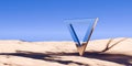 Modern chrome retro triangle frame object in surreal abstract desert landscape with blue sky background, geometric primitive