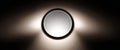 Modern circular ceiling light fixture emitting soft white light with symmetrical shadows on dark background Royalty Free Stock Photo