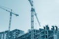 Modern city building under construction and yellow cranes against blue sky background Royalty Free Stock Photo