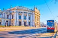 The modern city tram stops on Ringstrasse opposite entrance porch of Burgtheater, Vienna, Austria