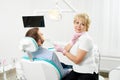 Modern clinic. Woman dentist looks into camera and holding tool