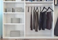 Modern closet with row of pants hanging in white wardrobe