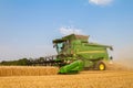 Modern combine harvester cutting crops corn wheat barley working golden field