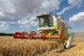 Modern combine harvester  harvesting on wheat field, cloudy sky Royalty Free Stock Photo