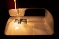 Modern compact electric sewing machine in the evening. View of needle and thread. Illumination from the built-in incandescent lamp Royalty Free Stock Photo