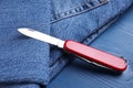 Modern compact portable multitool and jeans on blue wooden table