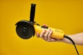 Modern, compact yellow angle grinder isolated on yellow background