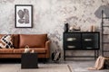 Modern composition of living room with brown sofa, mock up poster frame, dark commode, coffee table, basket, plaid. carpet,