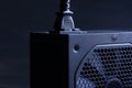 Modern computer AC power supply unit with a powerful fan and a connected power cable on a dark background. Fragment. A device for Royalty Free Stock Photo