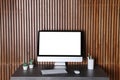 Modern computer monitor on desk against wooden wall Royalty Free Stock Photo