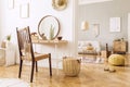 Modern concept in design home interior of open space with wooden desk, coffee table, sofa, chair, plants, mirror, macrame.