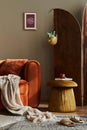 Modern concept of domestic interior with design sofa, wooden room screen, pillow, blanket, picture frame, side fancy pouf.