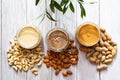 The modern concept of wellness and veganism. Jars of almond, cashew and peanut butter on a white wooden table with an olive branch