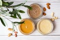 The modern concept of wellness and veganism. Jars of almond, cashew and peanut butter on a white wooden table with an olive branch