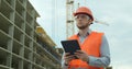 Modern construction engineer or architect in helmet at construction site works with industrial electronic tablet. Close Royalty Free Stock Photo