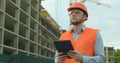 Modern construction engineer or architect in helmet at construction site works with industrial electronic tablet. Close Royalty Free Stock Photo